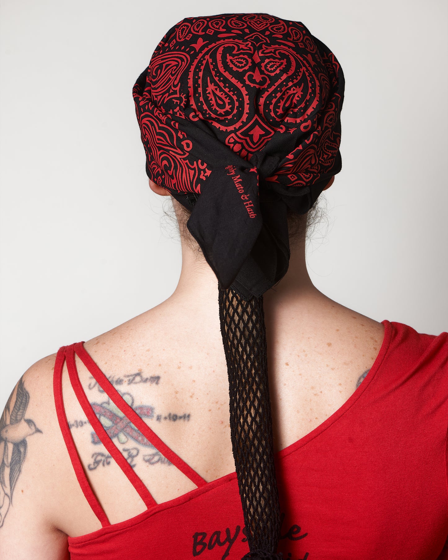 Extra Thin Black Headband, shown under black and red bandana (not included), back view, Female model.